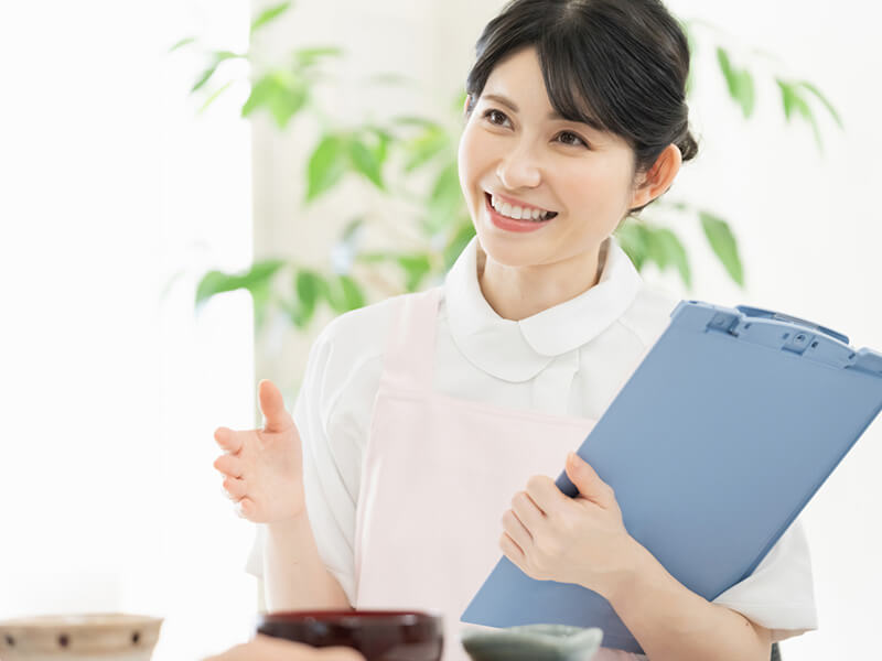 クリップボードを持ったエプロン姿の女性