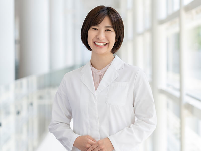 白衣を着た女性医師が正面を向いてニコッとしている様子